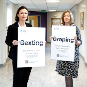 Clare McNaught and Jackie Andrews holding campaign posters showing the word "Sexting" and "Groping" cut through the middle with a scalpel 